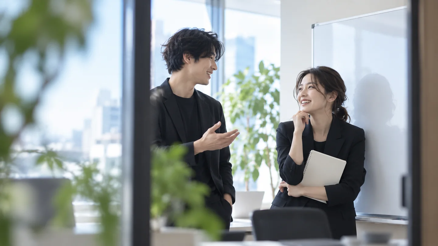 ホワイトボードの前で自然に会話する同僚